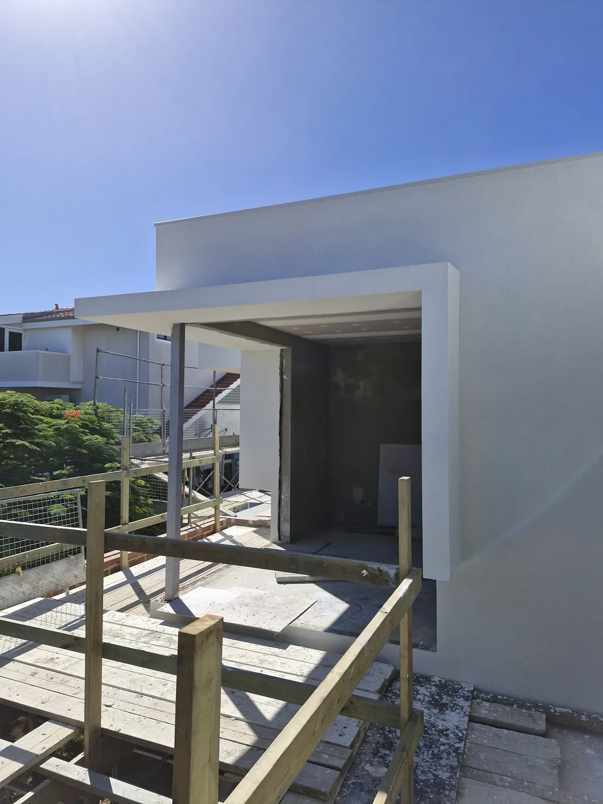 White textured opening surround and projecting head beside a timber scaffold railing.