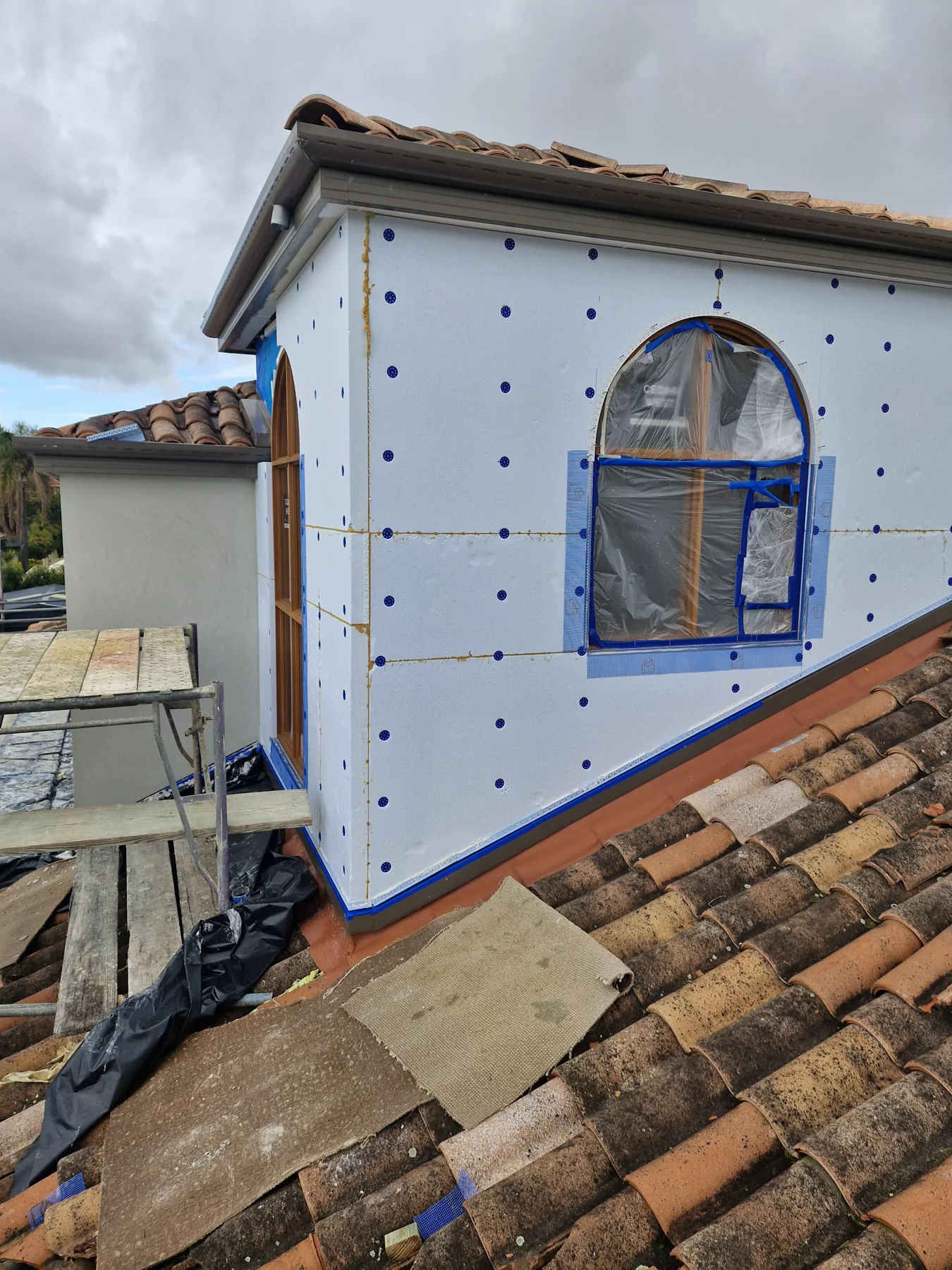 White cladding panels with fixings around an arched window opening