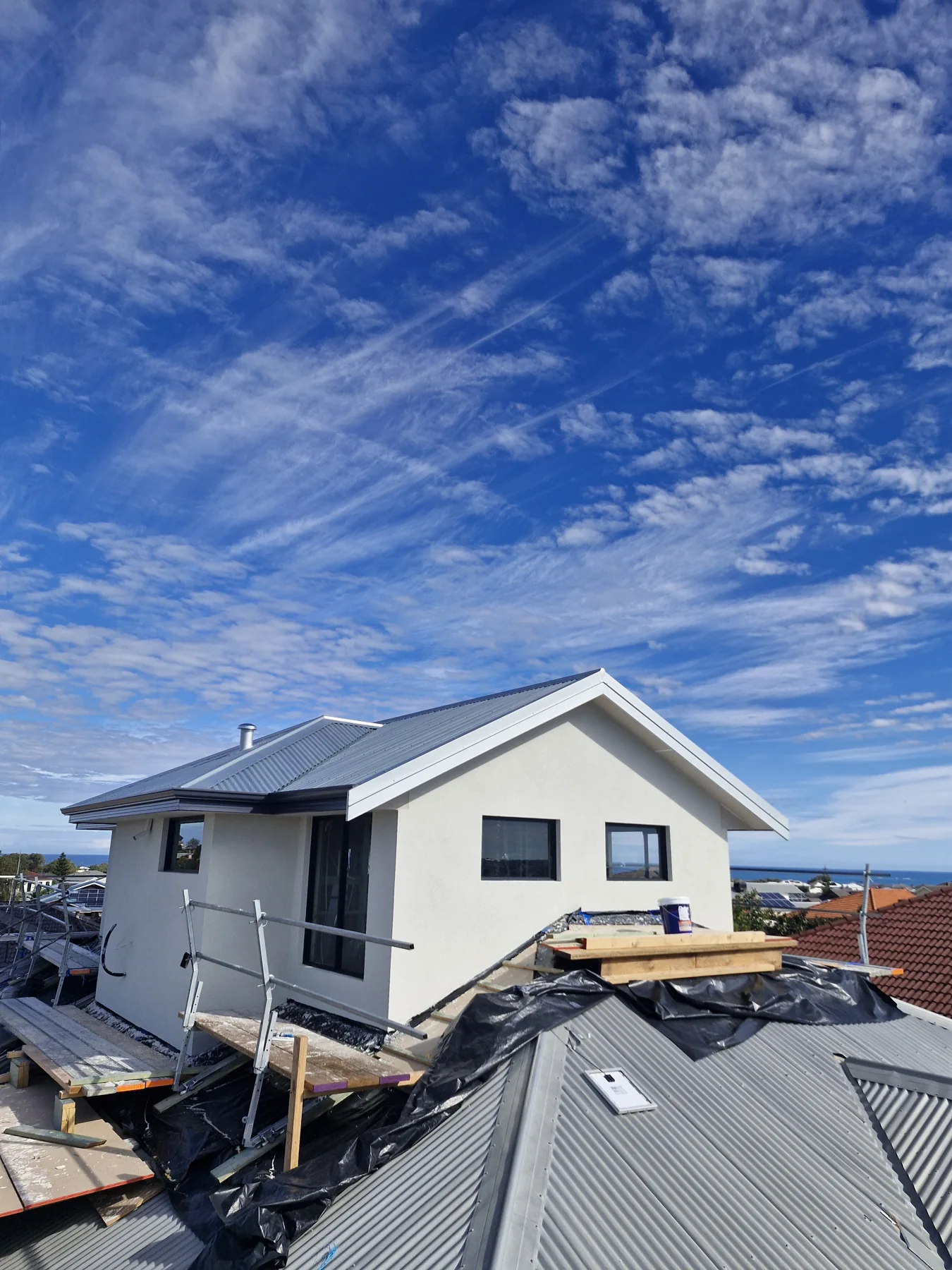 White coated upper-storey gable beside a metal roof